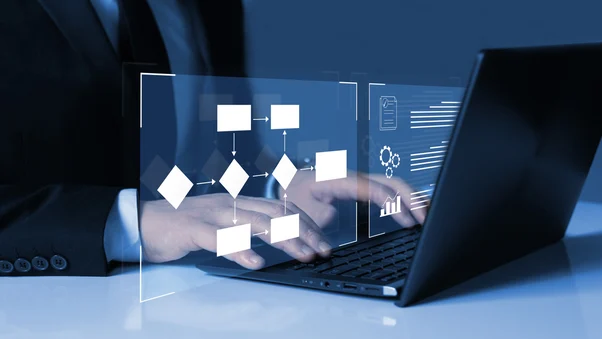 Mãos digitando em notebook com fluxograma de processos projetado, representando a otimização de processos com a Maxxi