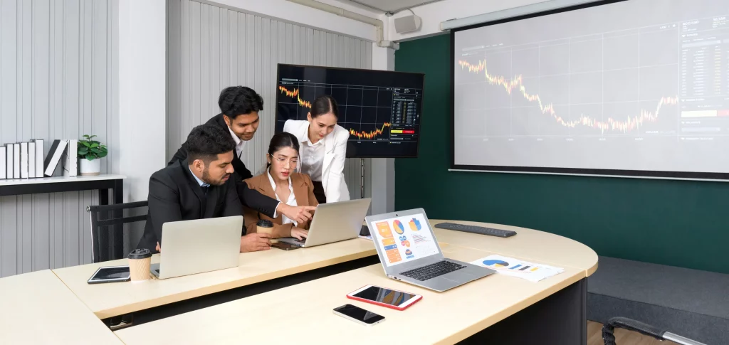 Equipe reunida analisando gráficos em notebooks e telões