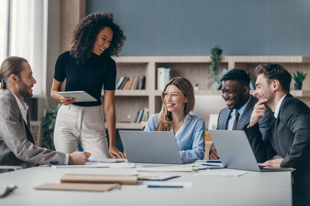 Equipe reunida em mesa de escritório com notebooks, discutindo um projeto