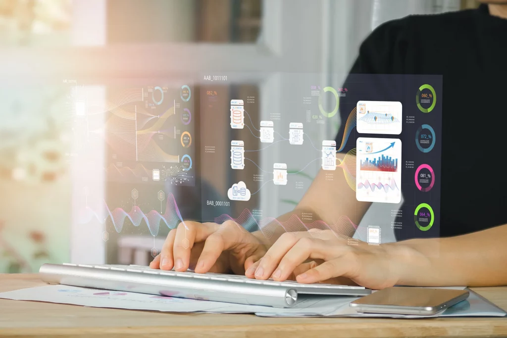 Mãos digitando em teclado com gráficos e indicadores de dados projetados