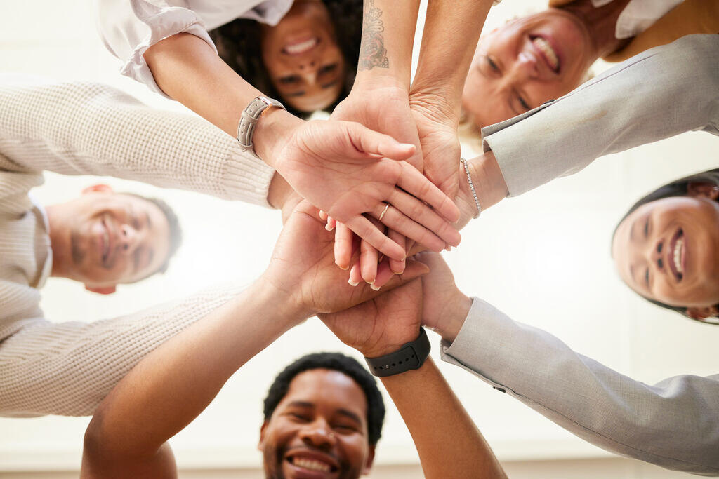 Equipe unindo as mãos em círculo, simbolizando parceria e colaboração